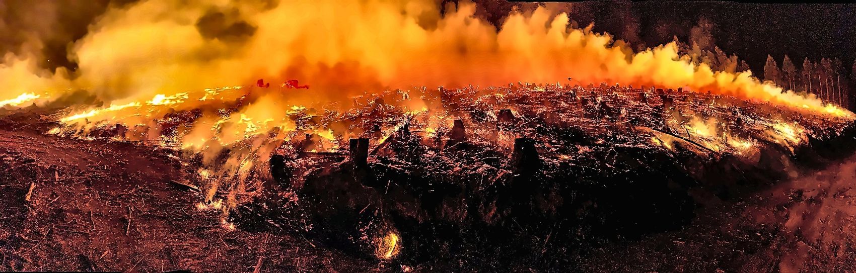 A fire line burning along a dark ridge at night